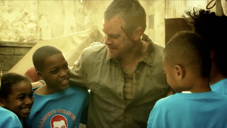 Matt Damon poses with a group of African children wearing shirts that read "Damon's Children" in "House of Lies"