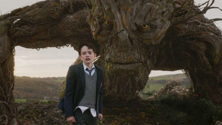 Lewis MacDougall as Conor standing next to the Yew Tree Monster in A Monster Calls