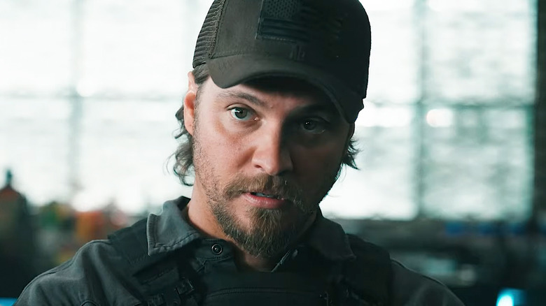 Luke Grimes' Kayce Dutton looks across frame as he stands in an armory in Marshals