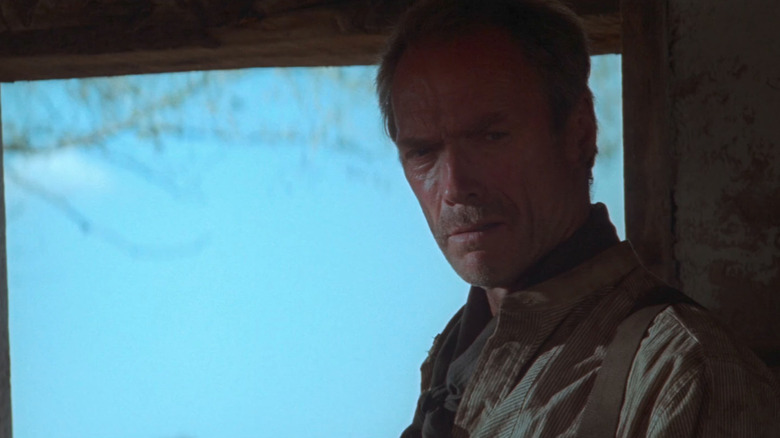 Clint Eastwood's William Munny stands by a window in Unforgiven