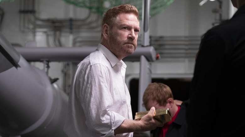 Kenneth Branagh as Sator holding gold bars in Tenet