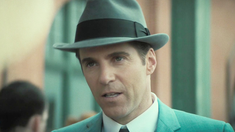Alessandro Nivola as Dickie Moltisanti wearing a hat and suit outside in The Many Saints of Newark