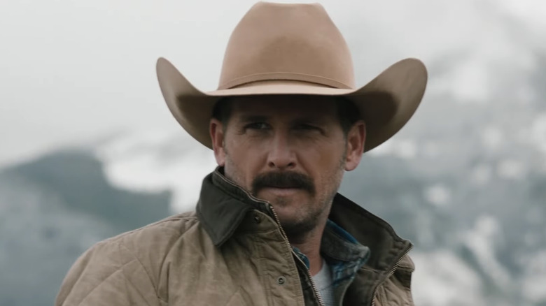 Josh Lucas' John Dutton is seen outside with mountains in the background in Yellowstone