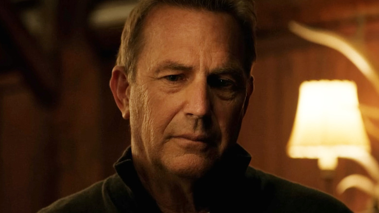 Kevin Costner's John Dutton looks down in closeup as he stands in his cabin in Yellowstone