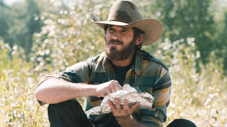 Dave Annable's Lee Dutton sits outside eating fish in Yellowstone