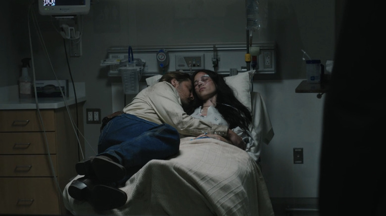 Luke Grimes' Kayce Dutton lays alongside Kelsey Asbille's Monica Dutton on a hospital bed in Yellowstone