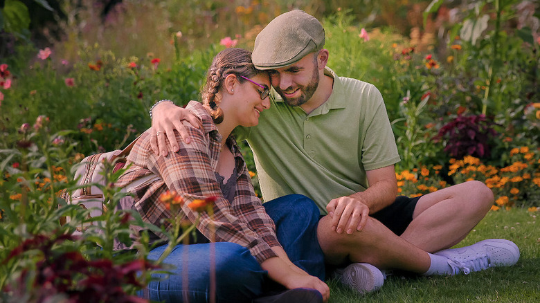 Connor Tomlinson & Georgie Harris embrace while sitting in a park in Love on the Spectrum season 4