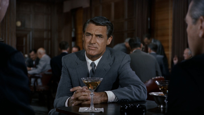 Cary Grant's Roger Thornhill sits at a table in front of a drink in North by Northwest