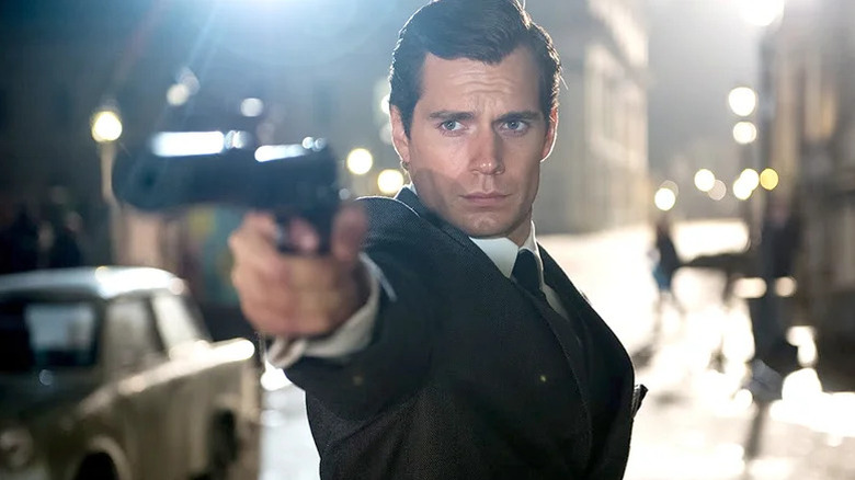 Henry Cavill's Napoleon Solo looks aims a pistol towards camera in The Man From UNCLE