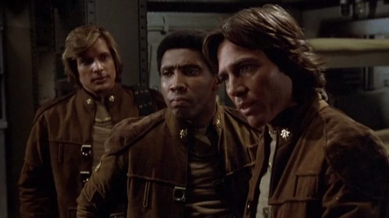 Starbuck (Dirk Benedict), Boomer (Herbert Jefferson Jr.), and Apollo (Richard Hatch) stand in their flight jackets in Battlestar Galactica (1978)