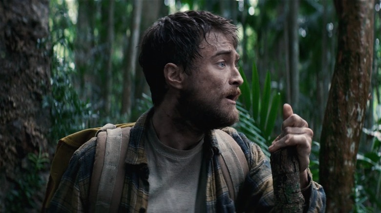 Dirty Daniel Radcliffe walking through a green jungle