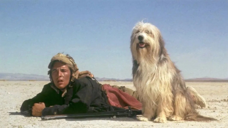 Vic on his stomach in the desert naext to his dog Blood in A Boy and His Dog