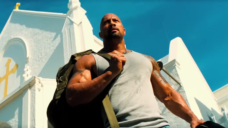 Dwayne Johnson as Paul Doyle, carrying a bag in front of a church in Pain and Gain