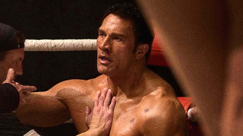 Dwayne Johnson as Mark Kerr, sitting against the ropes of a fighting ring in The Smashing Machine