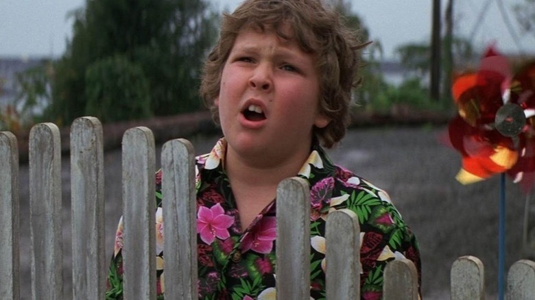 Chunk Cohen (Jeff Cohen) groans by a fence in The Goonies