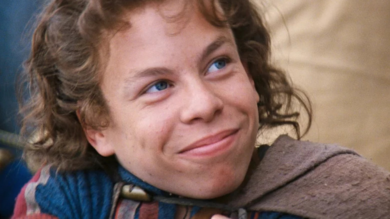 Willow Ufgood (Warwick Davis) smiles heartily while looking up in Willow