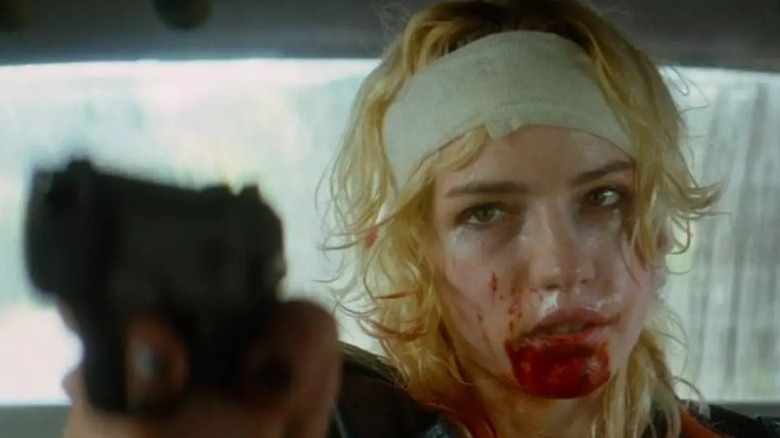 Willa Fitzgerald as the Electric Lady, holding a gun with a bandaged forehead, in Strange Darling