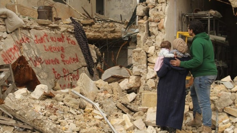 family surrounded by rubble destruction