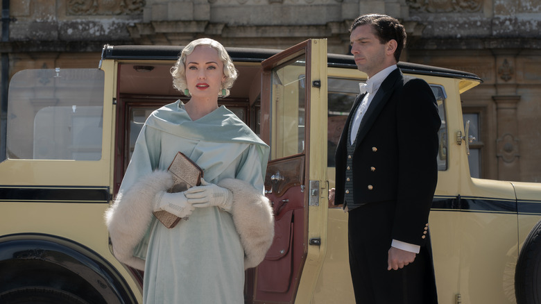 Laura Haddock as Myrna Dalgleish getting out of the car as Michael Fox as as Andy Parker holds open the door in Downton Abbey: A New Era