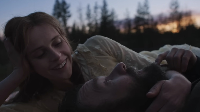 Felicity Jones as Gladys Grainier looks at Joel Edgerton as Robert Grainier as they lay together outside in Train Dreams