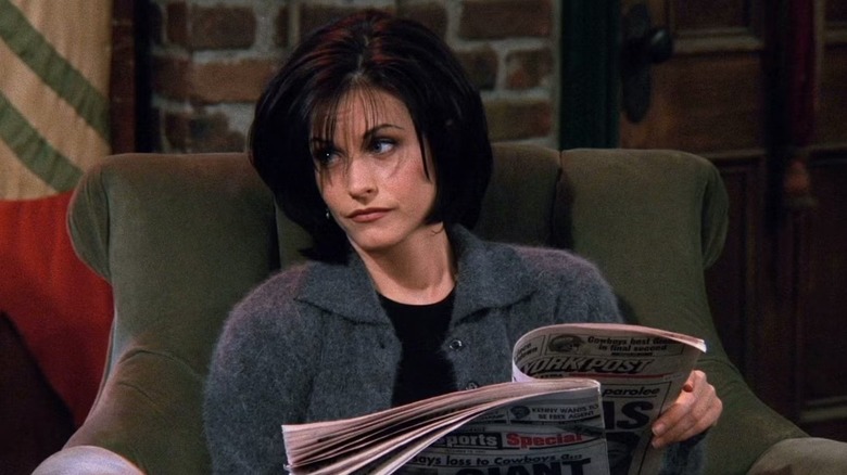 Monica reads a newspaper in friends