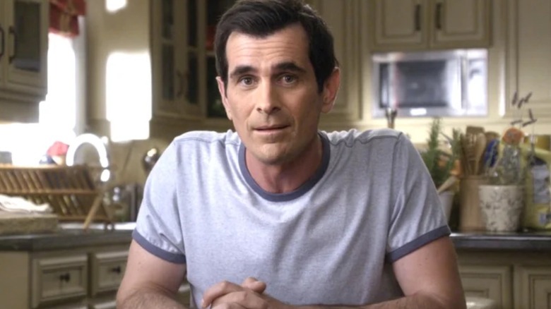 Phil Dunphy sat in kitchen looking at camera
