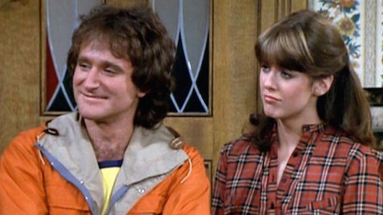 Robin Williams as Mork and Pam Dawber as Mindy stand at the threshold of a house in Mork & Mindy