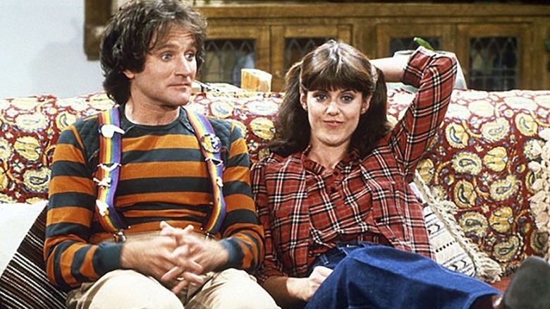 Robin Williams as Mork and Pam Dawber as Mindy hang out on the couch in Mork & Mindy