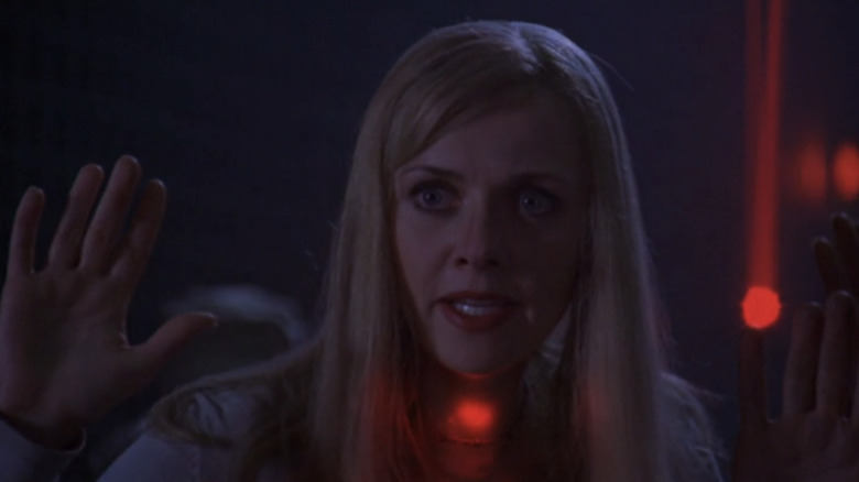 An alternate version of Amanda Tapper's Samantha Carter holds her hands up while illuminated by red light in Stargate SG-1