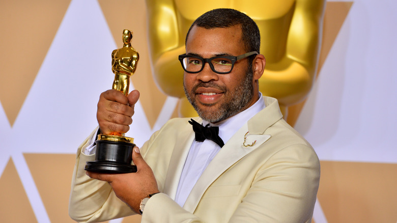 Jordan Peele holding his Oscar