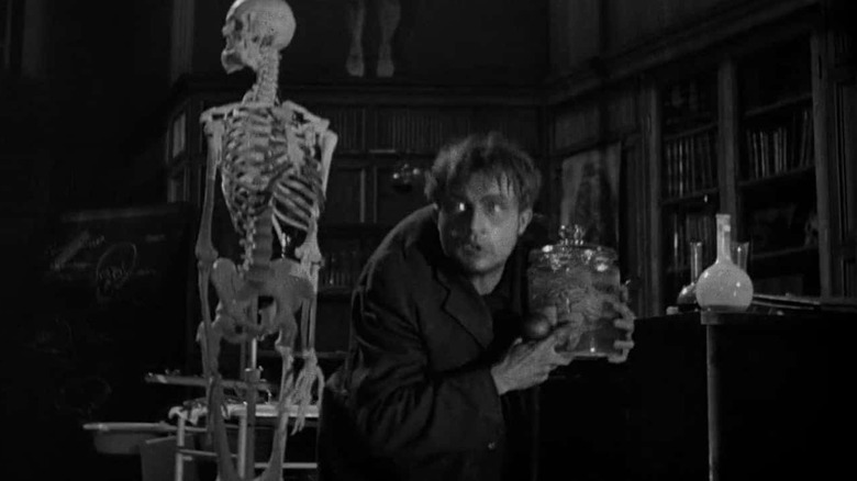 Fritz stealing a brain, with a skeleton behind him, in Frankenstein