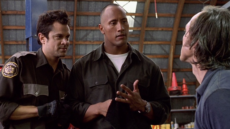 Ray and Chris talking to a bad guy in a warehouse in Walking Tall