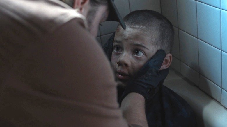 Brecken Merrill's Tate Dutton looks up at his father, Luke Grimes' Kayce Dutton in a bathroom in Yellowstone