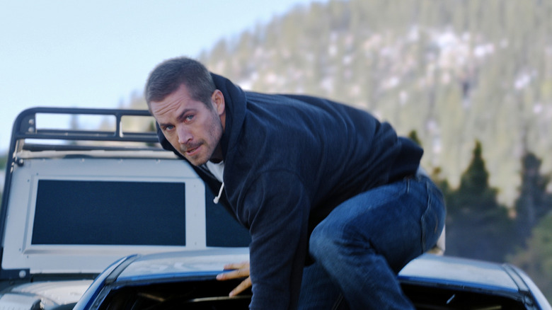 Brian O'Conner (Paul Walker) crouches on top of a vehicle in Furious 7