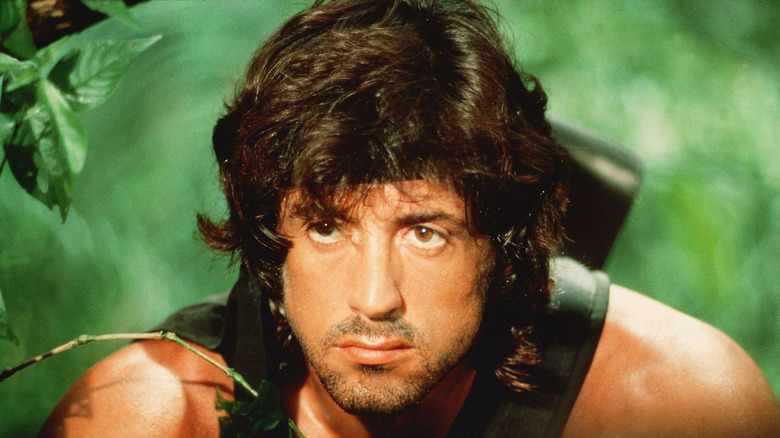 John Rambo sneaks through the woods in Rambo: The first of the second blood