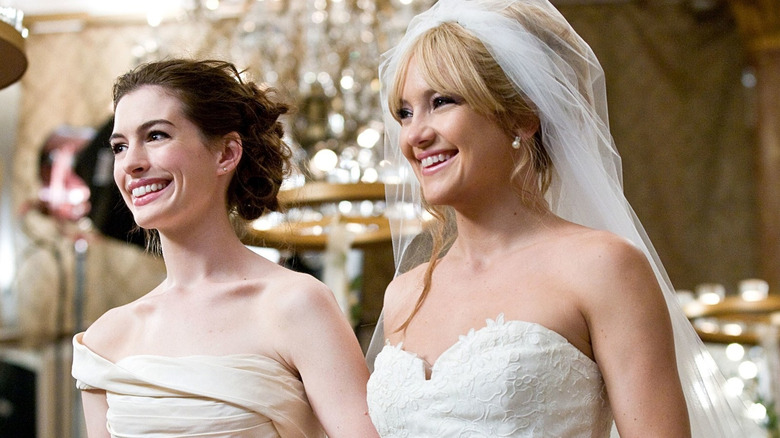 Emma and Liv smiling and walking down the aisle together in Bride Wars