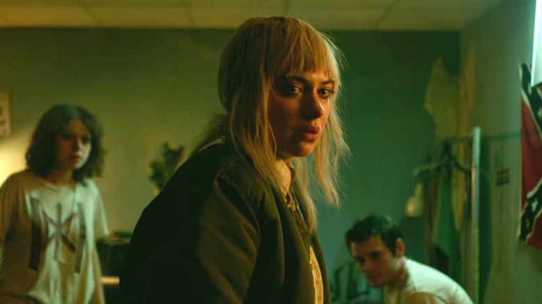 Imogen Poots as Emily in front of Alia Shawkat as Sam and Anton Yelchin as Pat in the green room in Green Room