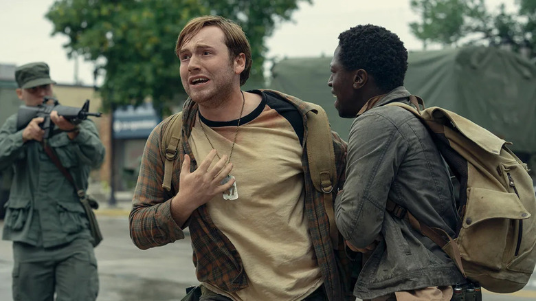 Ray is pulled away by Pete as a soldier takes aim in The Long Walk