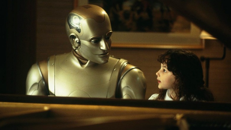 Andrew (Robin Williams), a sleek metallic robot, and Little Miss (Halle Eisenberg) sit at a grand piano in a warmly lit room, their faces turned to one another with curious expressions in Bicentennial Man