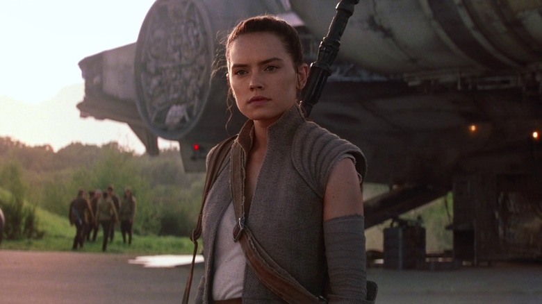 Daisy Ridley as Rey standing by the Millennium Falcon in Star Wars: The Force Awakens