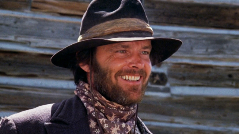 Tom Logan smiles from Jack Nicholson on the background covered with wooden panels