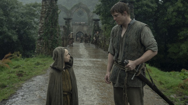 Dexter Sol Ansell as Egg standing next to Peter Claffey as Ser Duncan the Tall on a muddy road in the rain in A Knight of the Seven Kingdoms