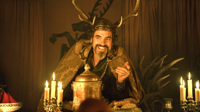Daniel Ings as Lyonel Baratheon wearing an antler crown and seated at a table lit by candles in A Knight of the Seven Kingdoms