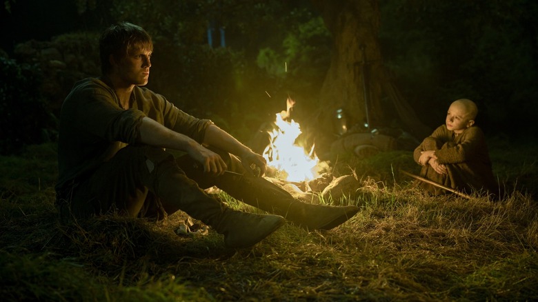 Peter Claffey as Ser Duncan the Tall sitting by a campfire next to Dexter Sol Ansell as Egg in A Knight of the Seven Kingdoms