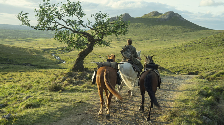 A wide shot of Peter Claffey as Ser Duncan the Tall leading three horses through the countryside in A Knight of the Seven Kingdoms