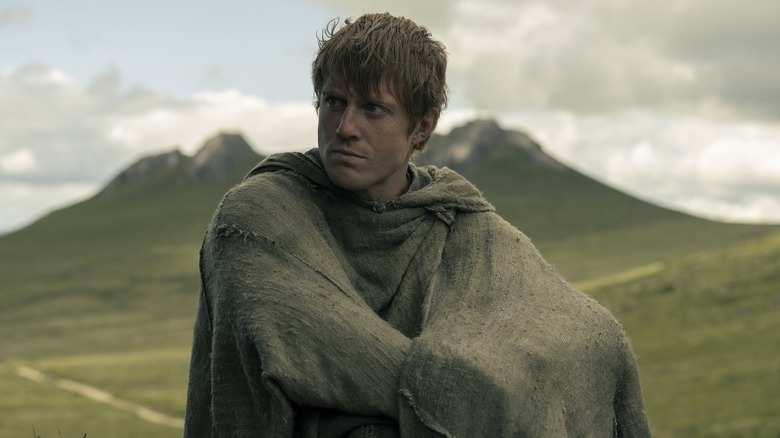 Dunk with a cloak around his body sulking in the middle of a field in A Knight of the Seven Kingdoms