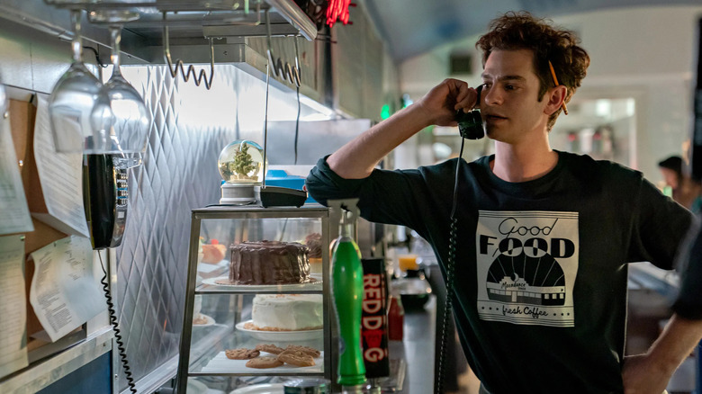 Jonathan Larson (Andrew Garfield) stands at a diner counter and holding a corded phone in tick, tick... BOOM!