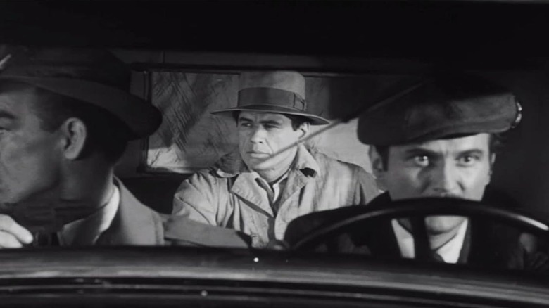 Charles Bronson as George Kelly sitting in the back of a vehicle in Machine-Gun Kelly