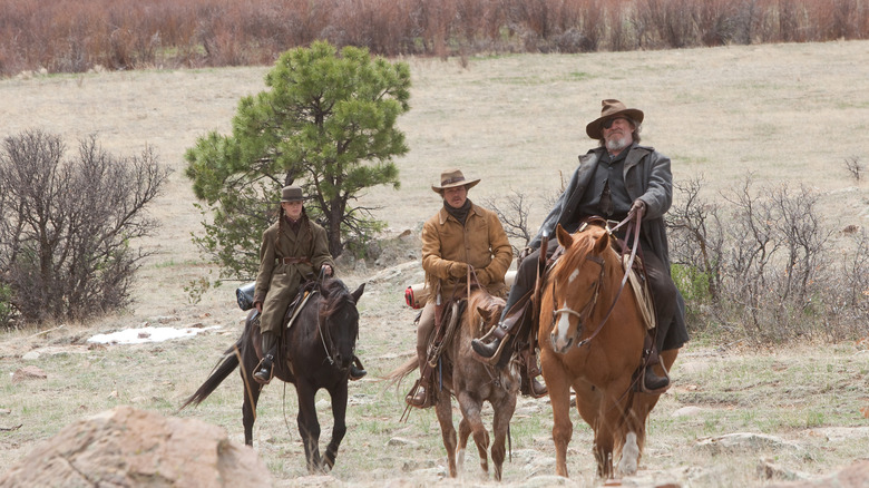 Jeff Bridges as Deputy U.S. Marshal Rooster Cogburn, Matt Damon as Texas Ranger LaBoeuf, and Hailee Steinfeld as Mattie Ross traveling on horseback through the wilderness in True Grit