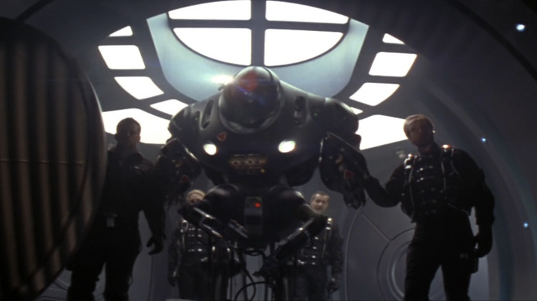 Matt LeBlanc's Major Don West stands beside a robot and William Hurt's Professor John Robinson in Lost in Space